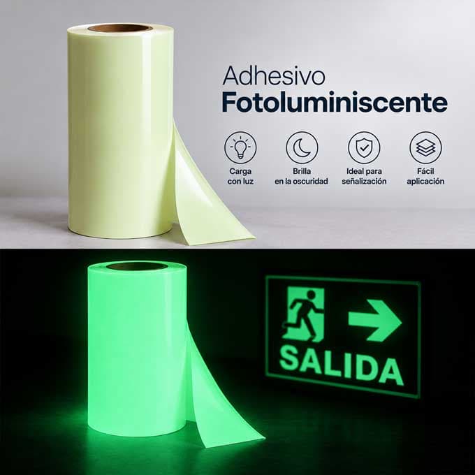 El mismo rollo de adhesivo fotoluminiscente dos veces: arriba a plena luz, color marfil, y abajo a oscuras brillando en verde junto a una señal de salida encendida