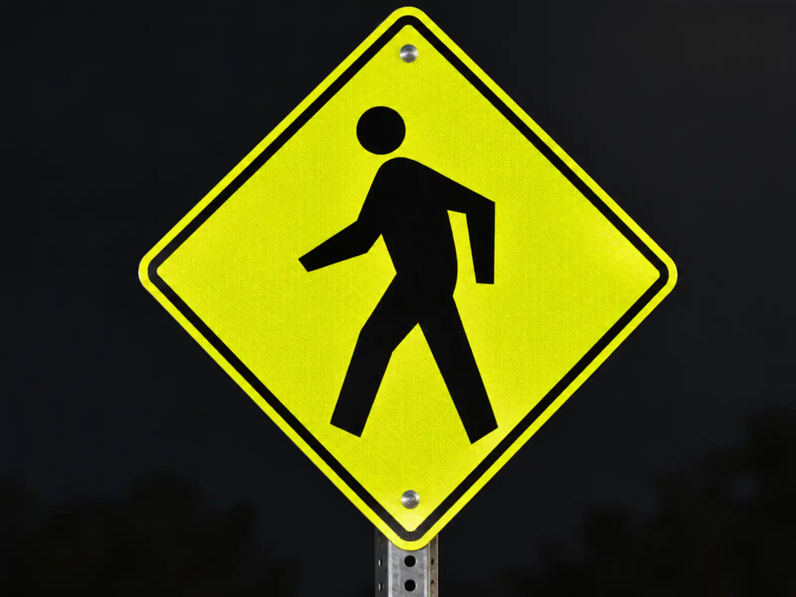 Señal de cruce peatonal en amarillo-verde fluorescente, de noche