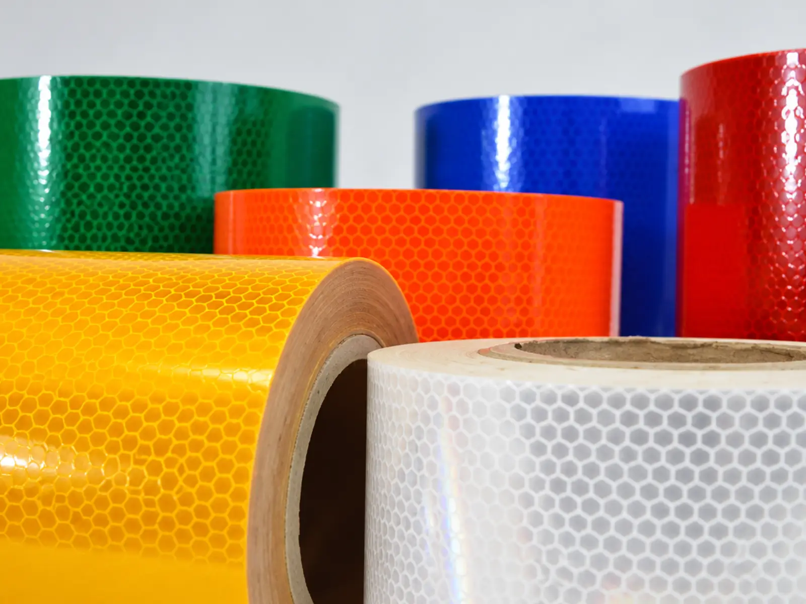Rollos de lámina prismática en verde, azul, rojo, naranja, amarillo y blanco, con el patrón de panal a la vista