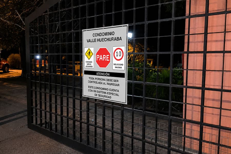 Letrero de normas de acceso instalado de noche en el portón de un condominio